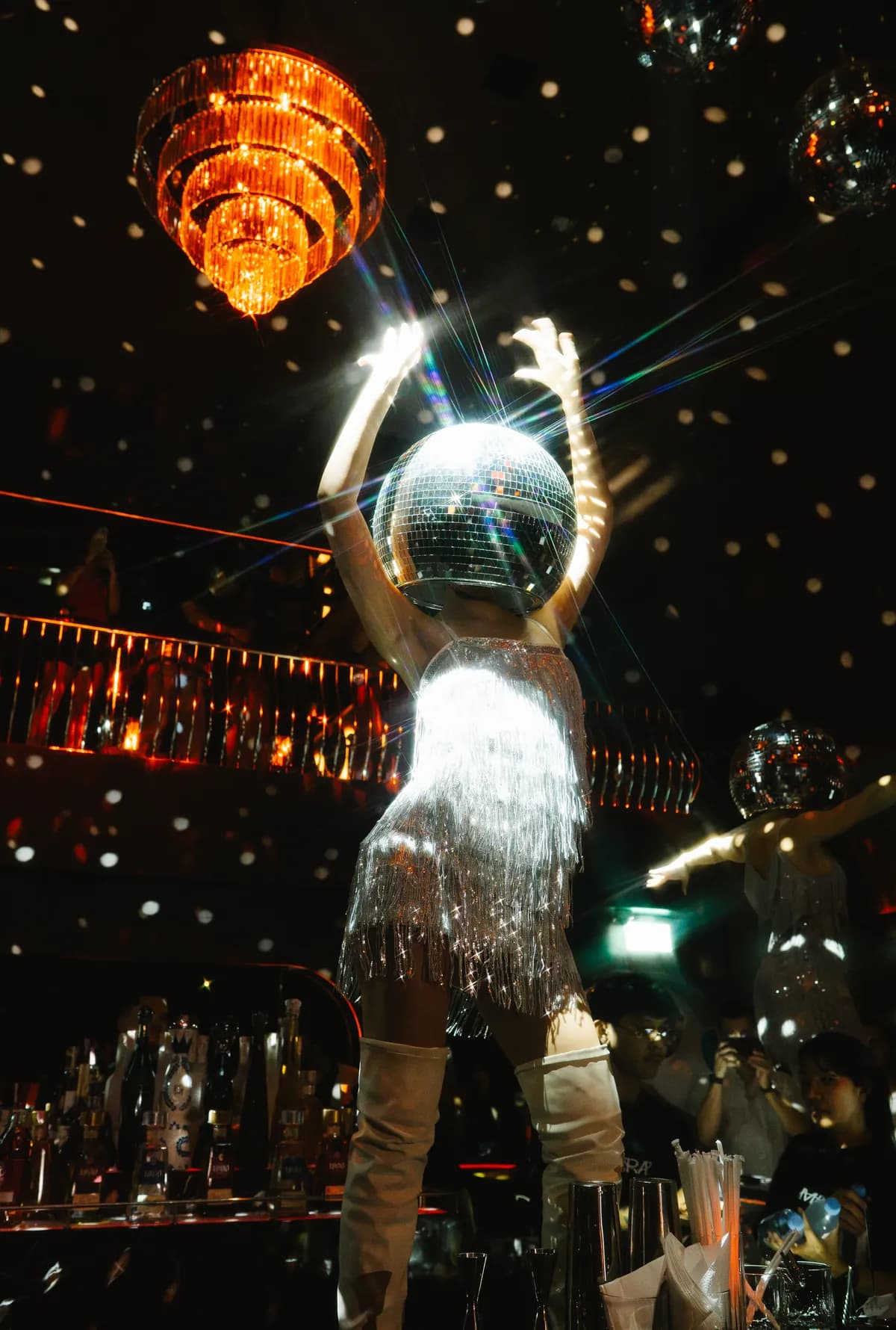 A dancer lifting a mirror ball above the crowd at MIRA